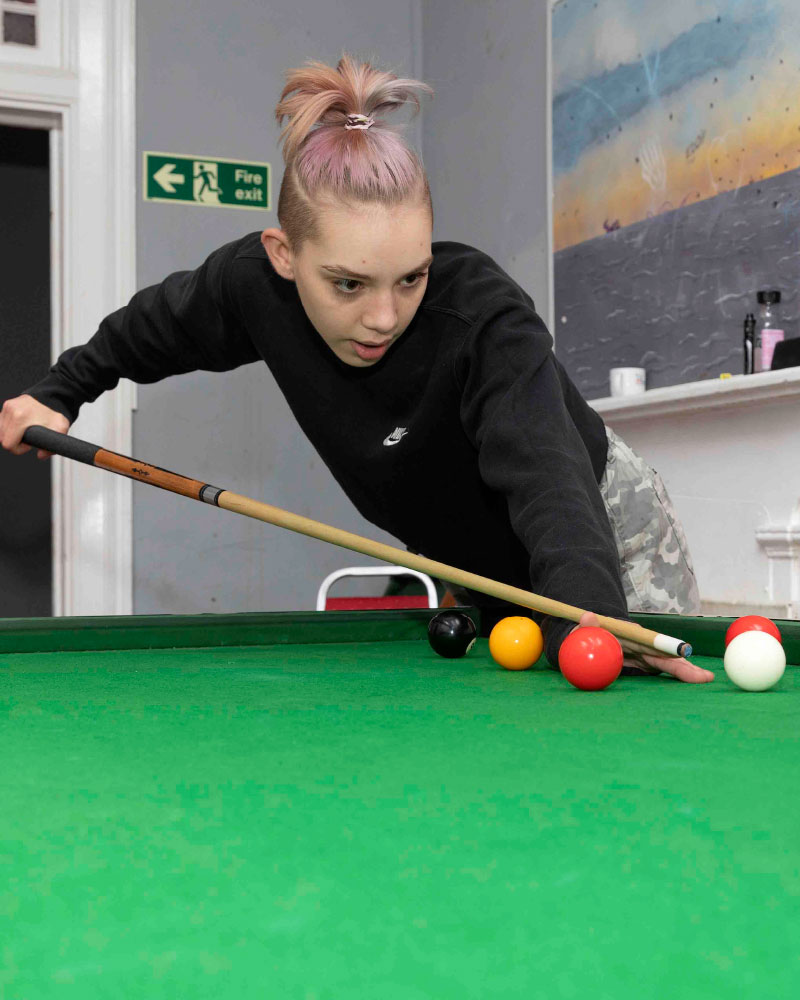 Young adult playing pool at one of our supported housing centres