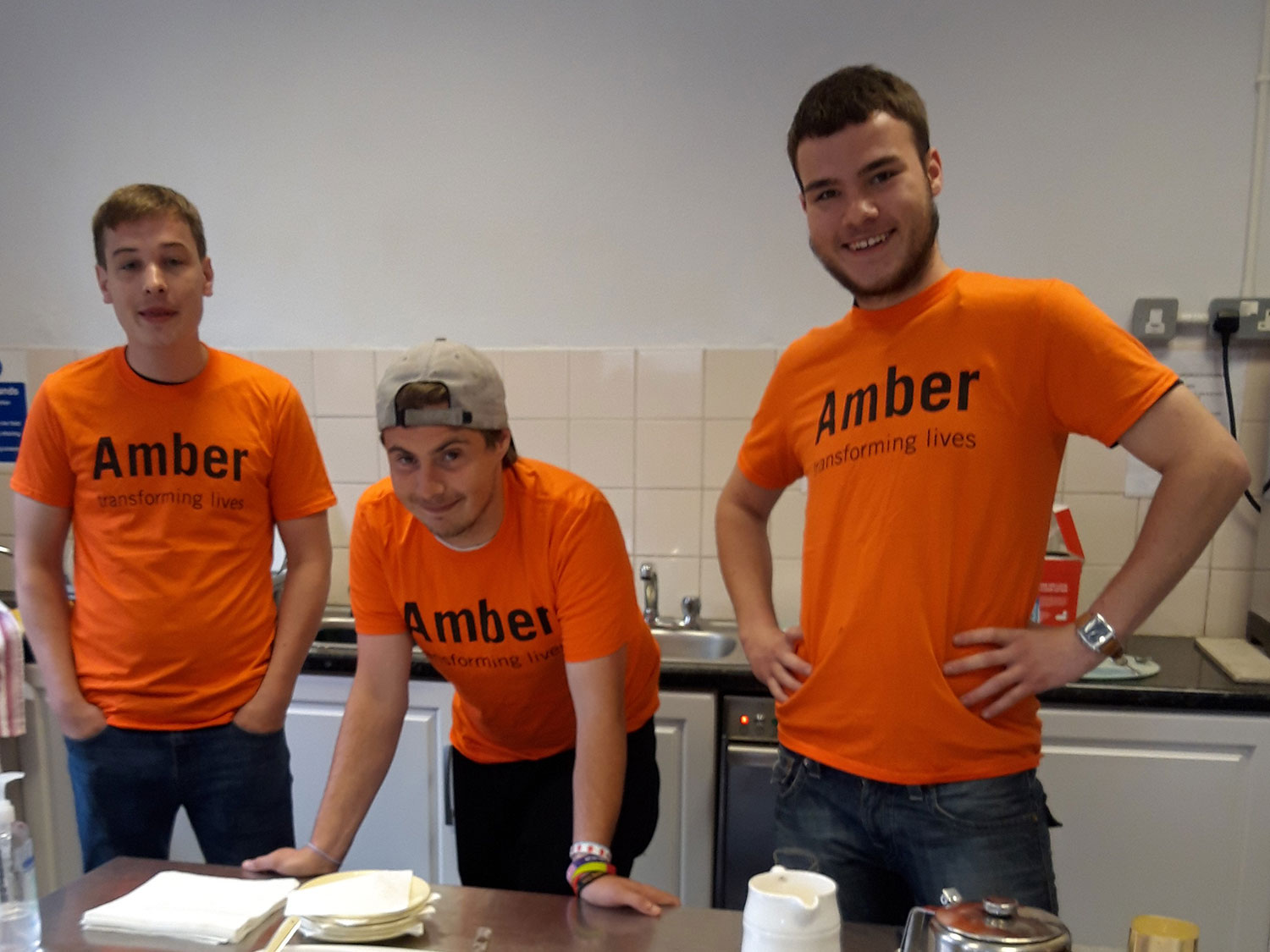 Three young adults wearing orange Amber Foundation t-shirts