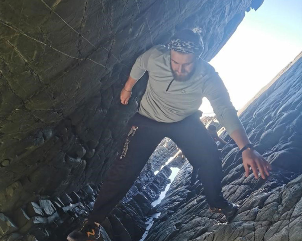 Young adults climbing between rocks