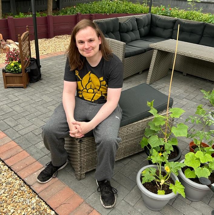 Young adult sat in garden area of our supported housing centre