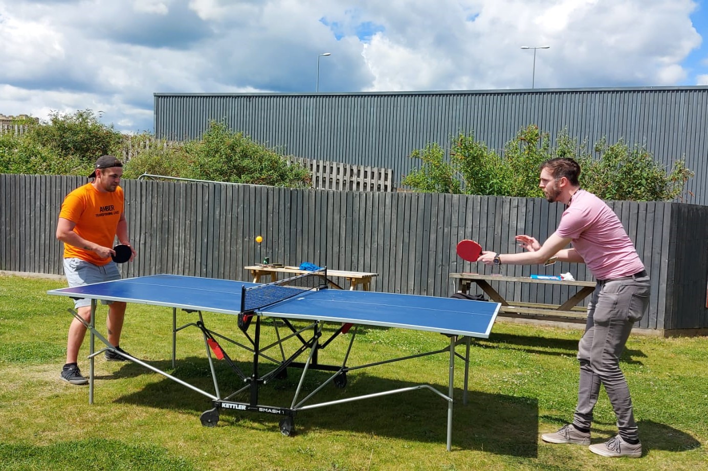 Two men playing table tennis in the sunshine